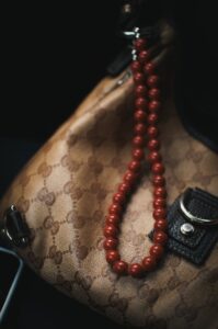 Close-up of a designer handbag adorned with red beads, highlighting luxury fashion.